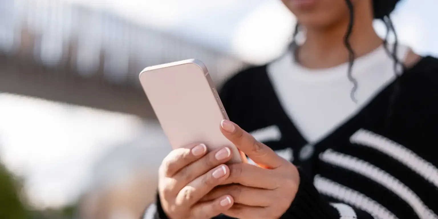 young-woman-holding-smartphone-outside-connecting-2025-10-16-01-54-10-utc